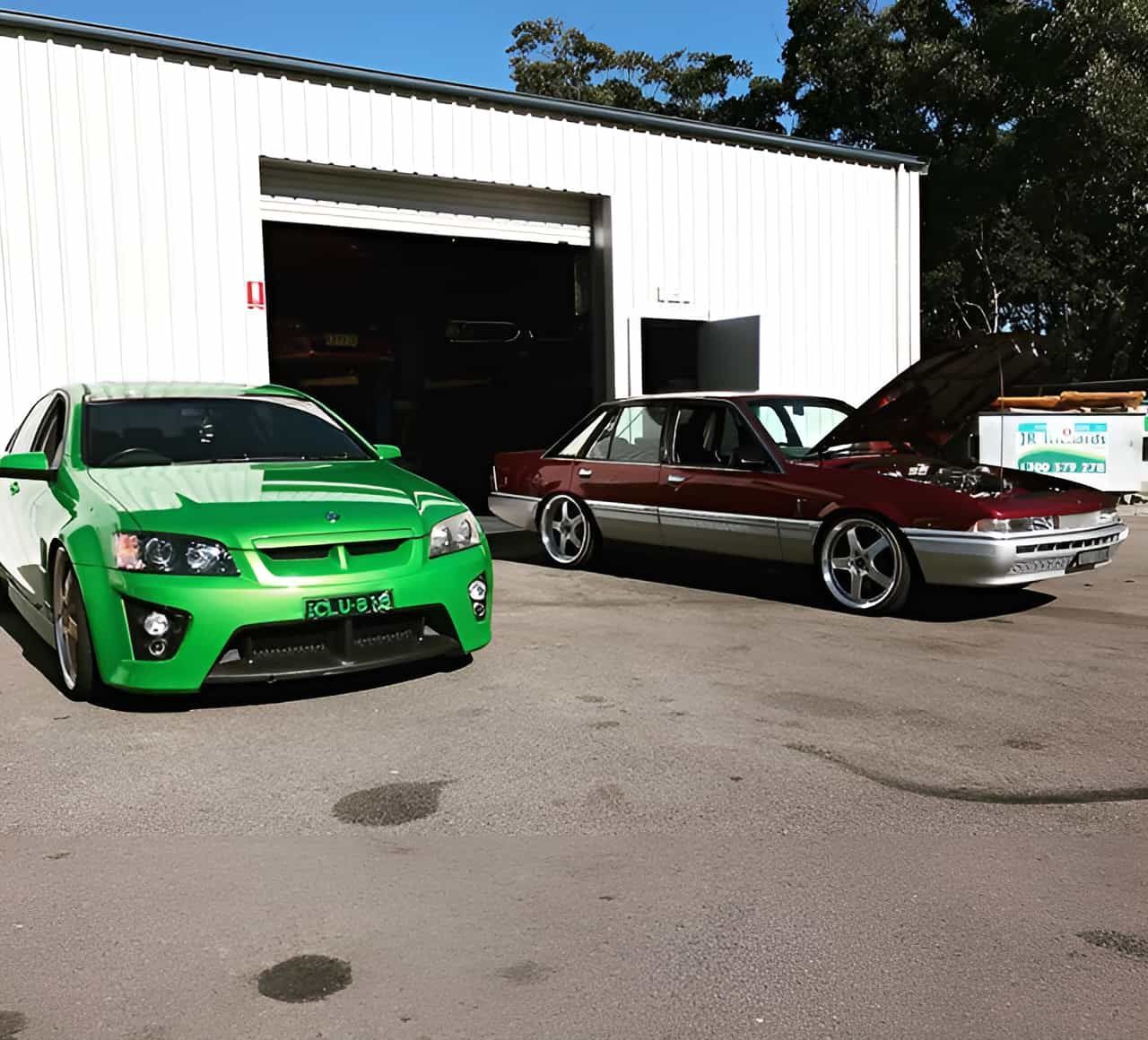 A Green Car And A Red Car Are Parked In Front Of A Garage — ProStreet Automotive & Fabrication In Cardiff, NSW