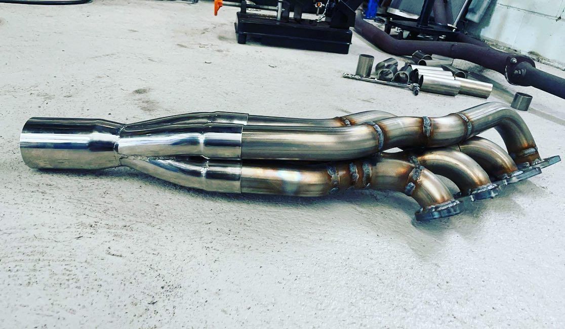 A Stainless Steel Exhaust Pipe Is Laying On The Ground — ProStreet Automotive & Fabrication In Cardiff, NSW