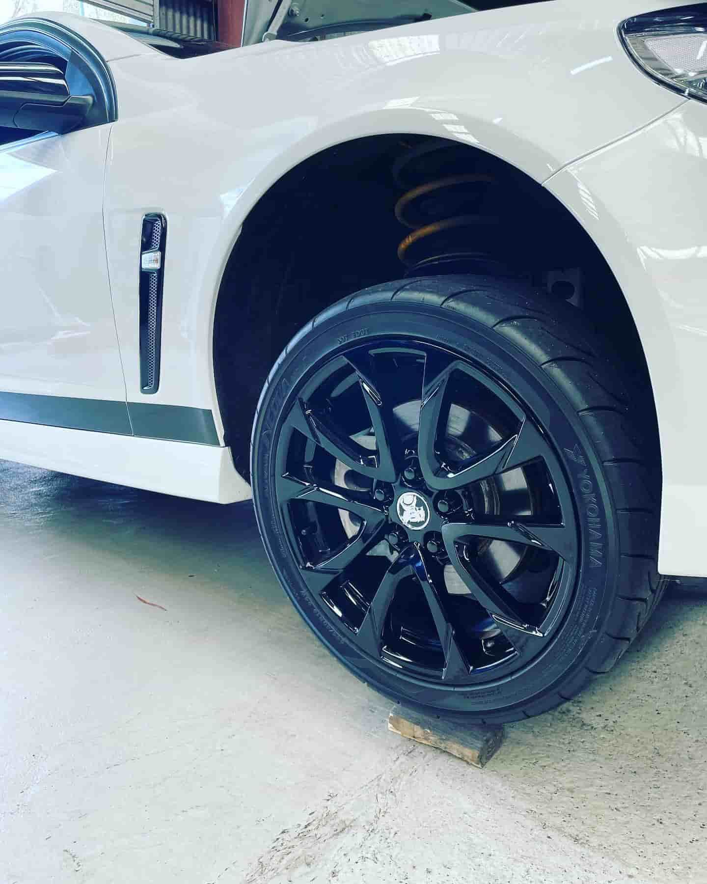 A White Car With Black Wheels And Tires Is Sitting On A Wooden Block — ProStreet Automotive & Fabrication In Cardiff, NSW