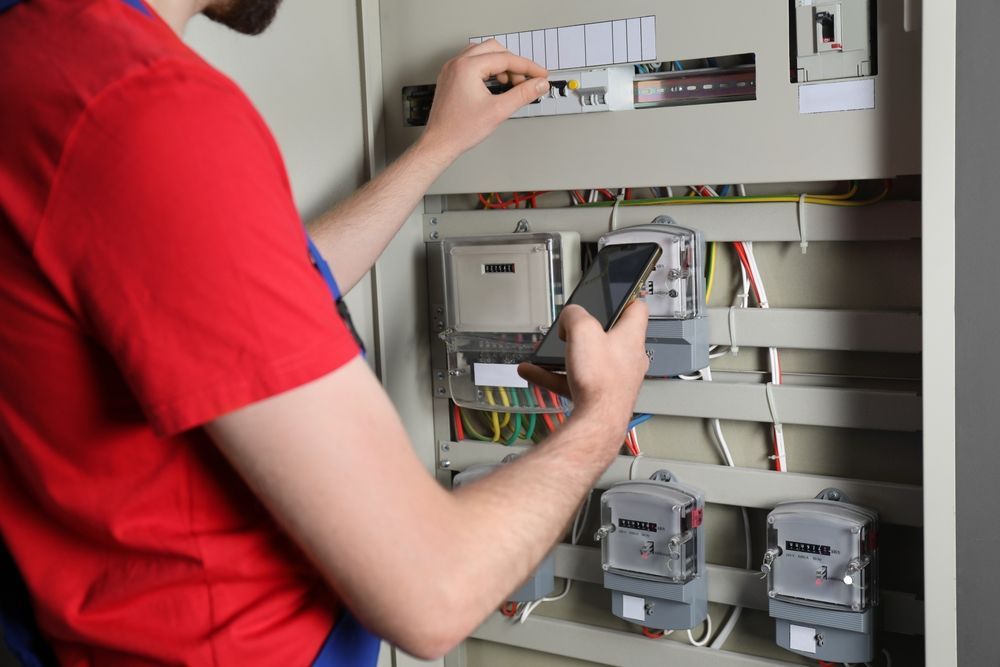 A man is using a cell phone to check a meter.