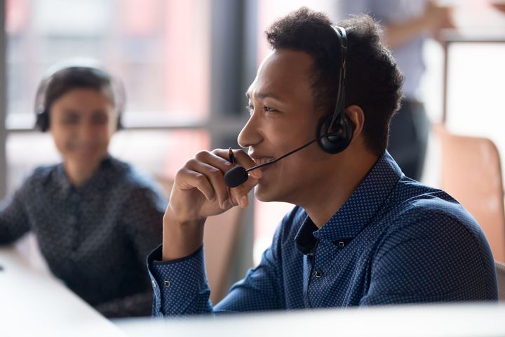 Cheerful customer service agents with headphones communicating with clients at call center