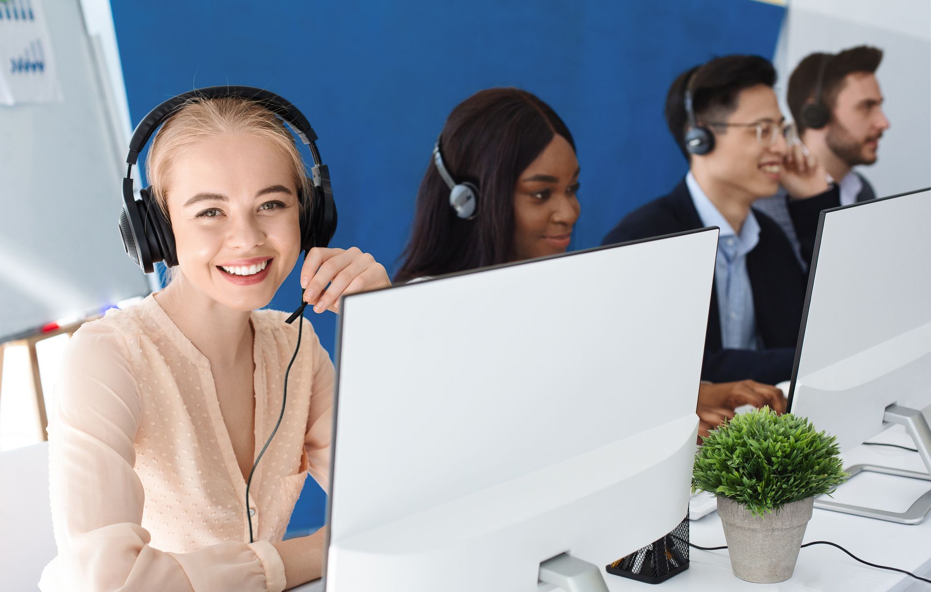 Cheerful customer service agents with headphones communicating with clients at call center