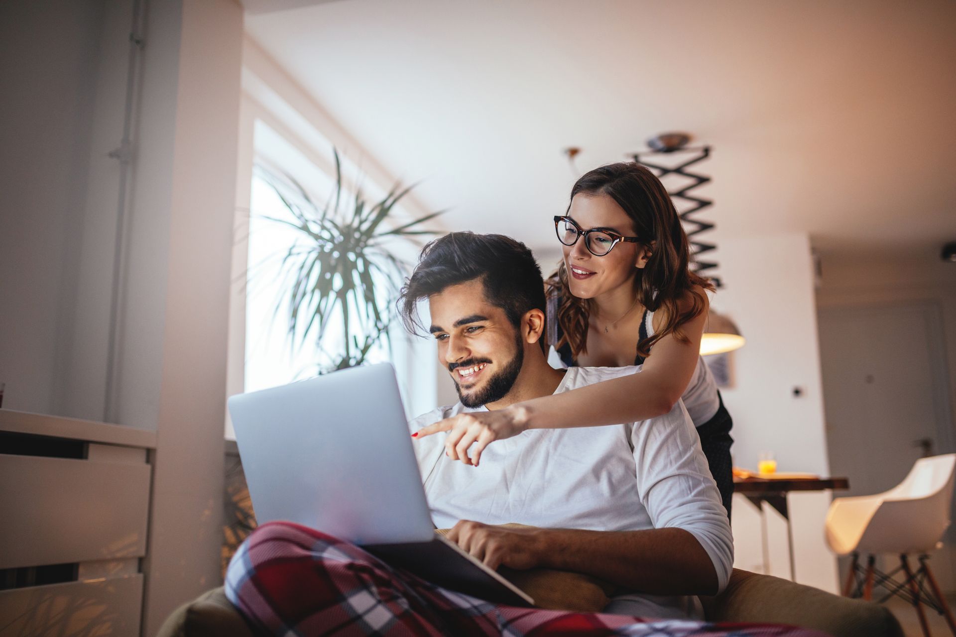 Shot of a happy young couple embracing while using laptop at home.