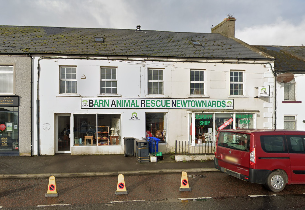 A red van is parked in front of a barn animal rescue newtownards store