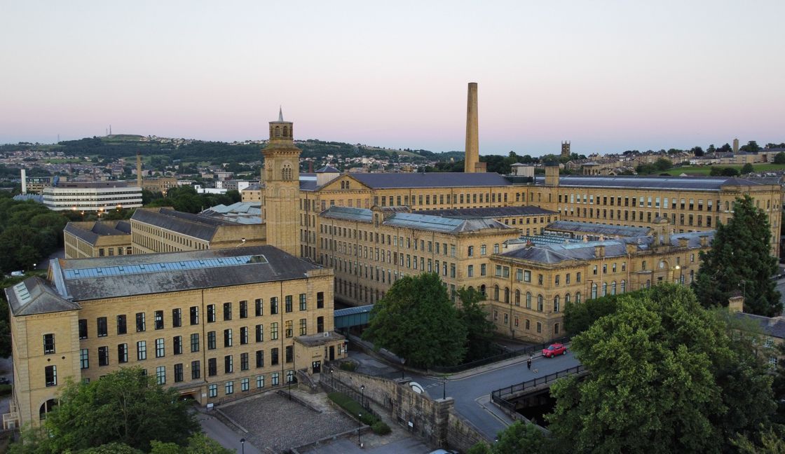 An aerial view of a large building with a clock tower and a chimney.