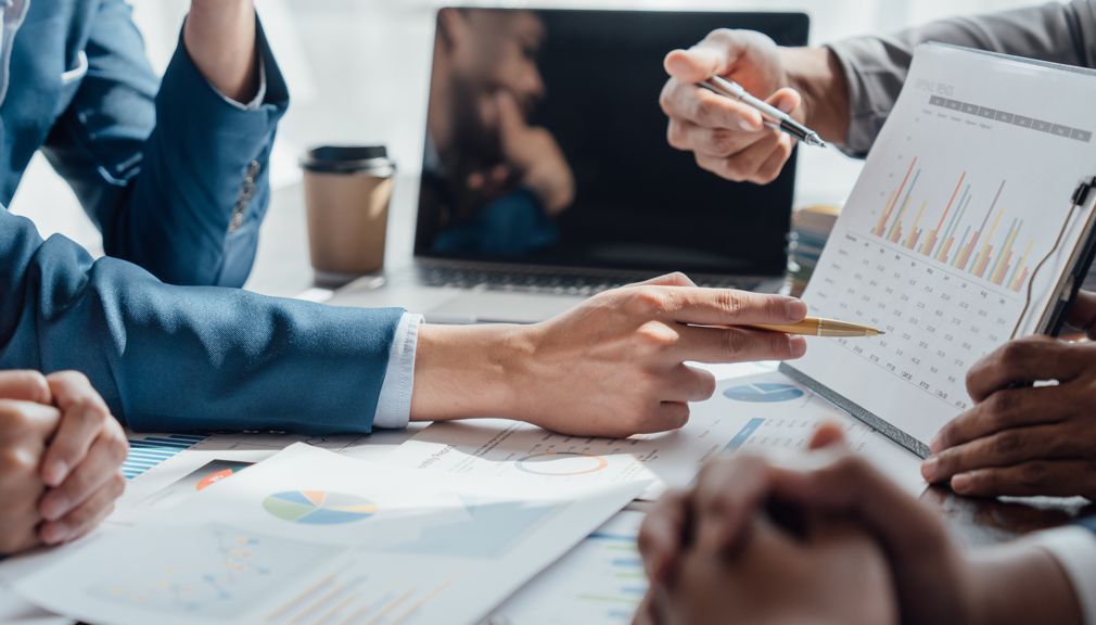 A group of people are sitting around a table looking at a graph.