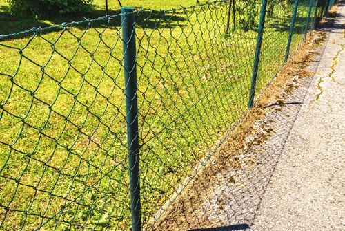 A chain link fence is along the side of a road.