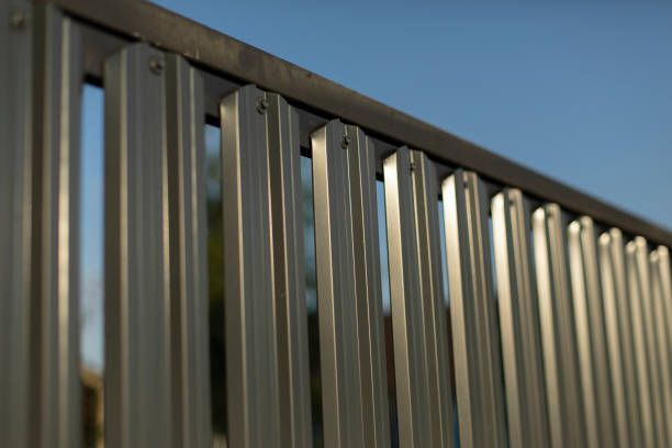 A close up of a metal fence with a blue sky in the background.