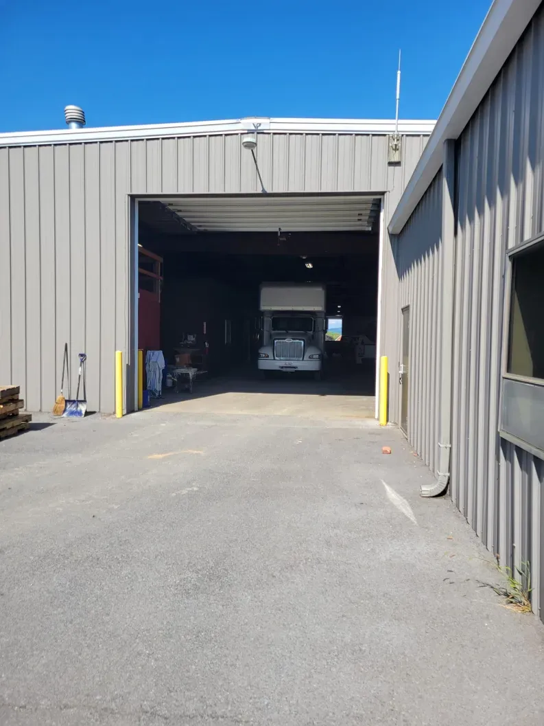 Open bay of a gray industrial building; a truck is inside.