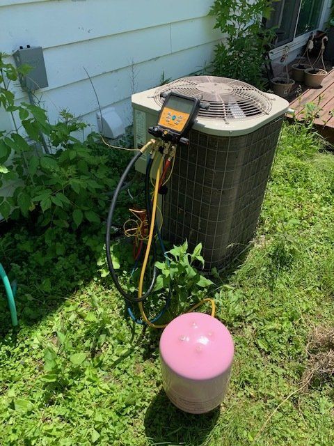 An air conditioner is sitting in the grass next to a balloon.