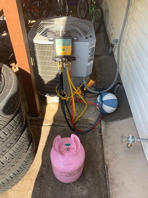 A propane tank is sitting next to an air conditioner.