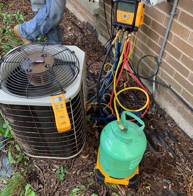 A man is working on an air conditioner next to a green cylinder