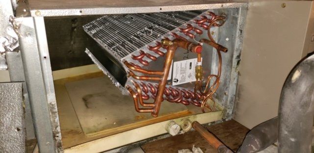 The inside of a refrigerator with copper pipes coming out of it.