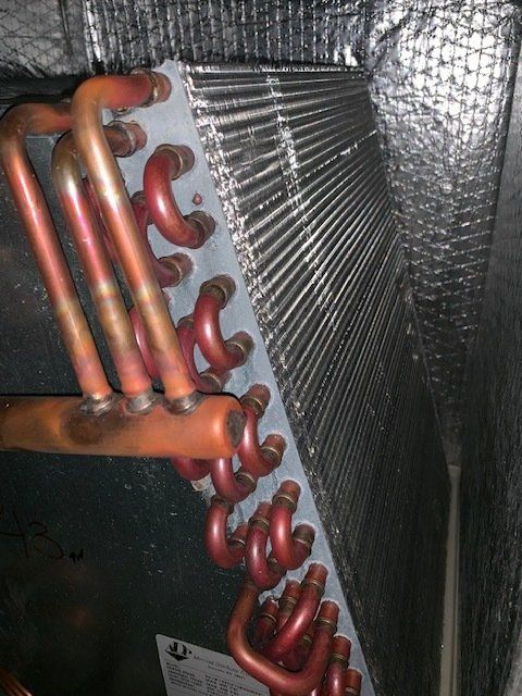 A close up of an air conditioner coil with red pipes