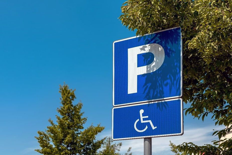 Blue handicap parking sign with a white 'P' and wheelchair symbol against a blue sky.