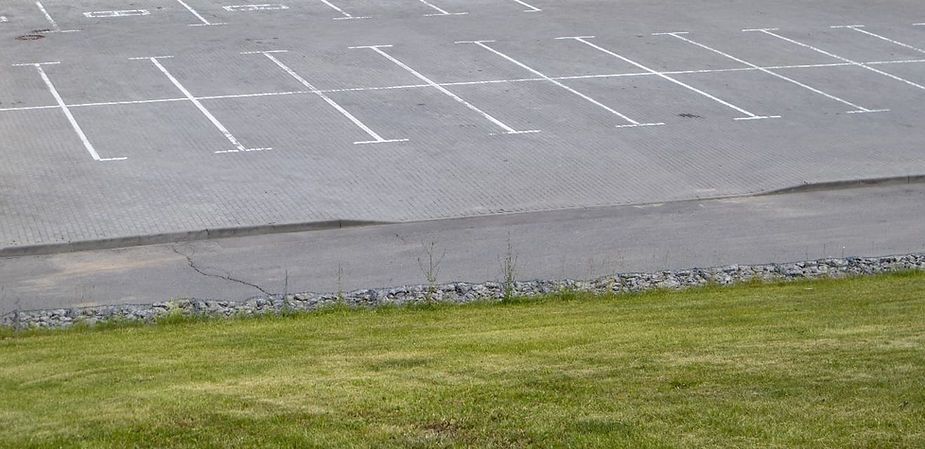 Empty parking lot next to green grass.