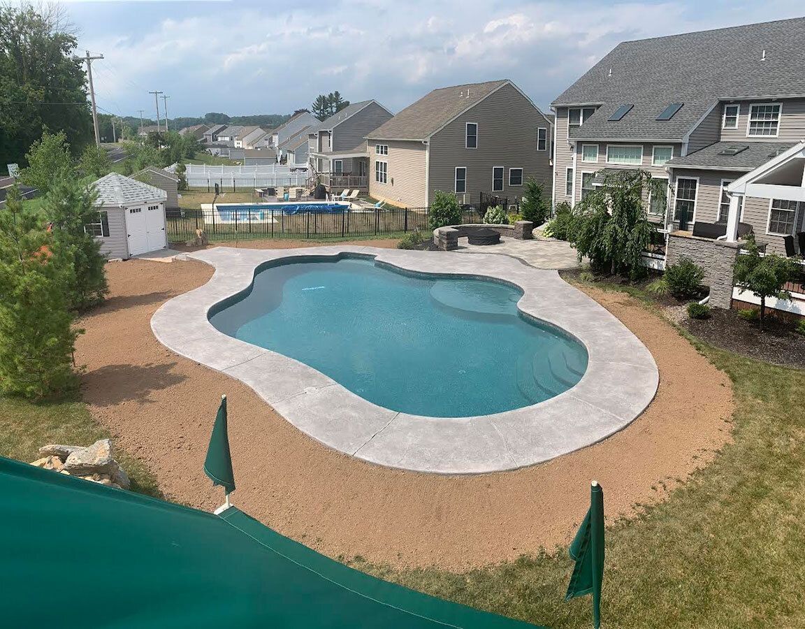an aerial view of a large swimming pool in a backyard surrounded by houses .