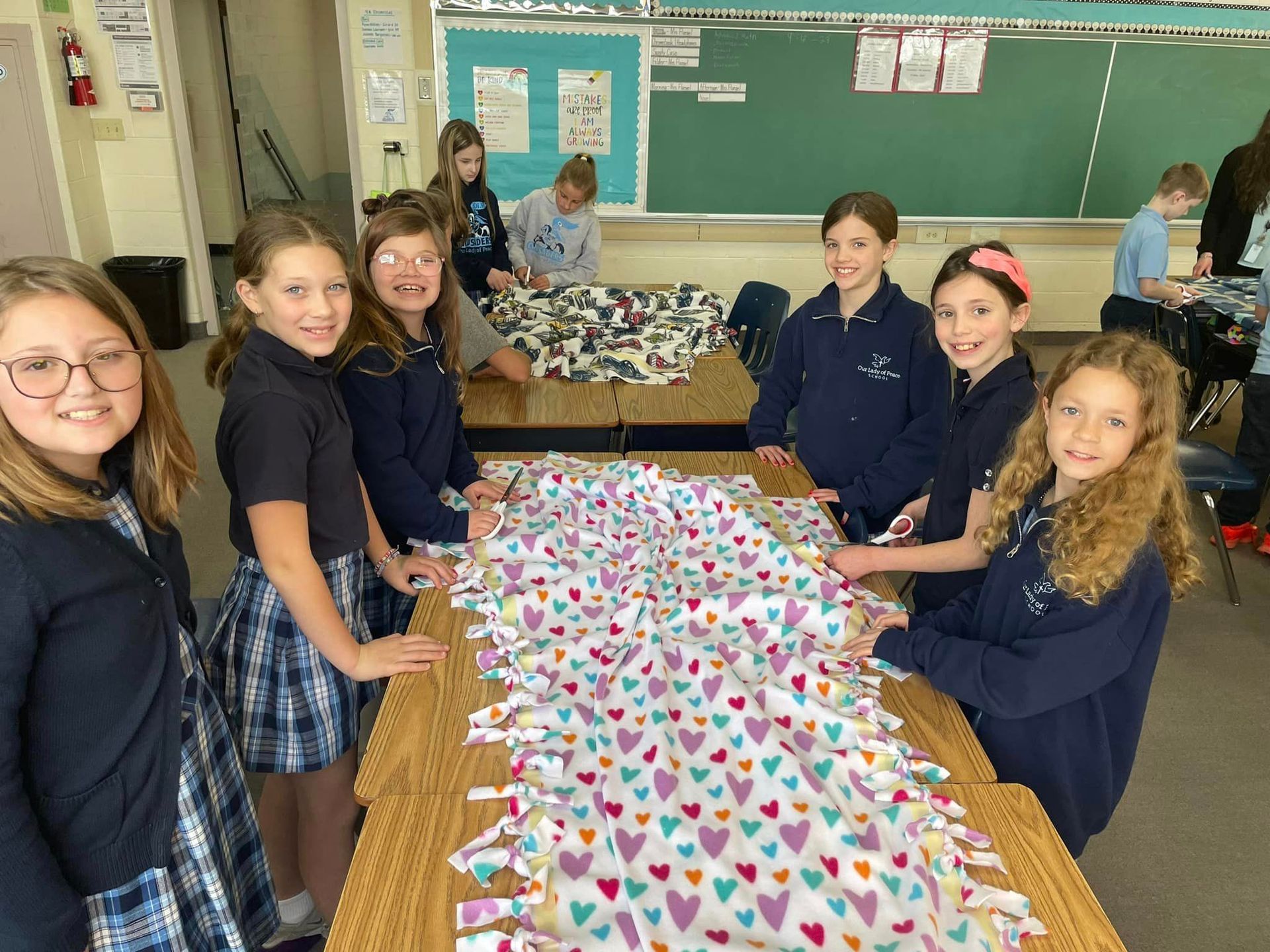 A group of young girls are sitting around a table with hearts on it