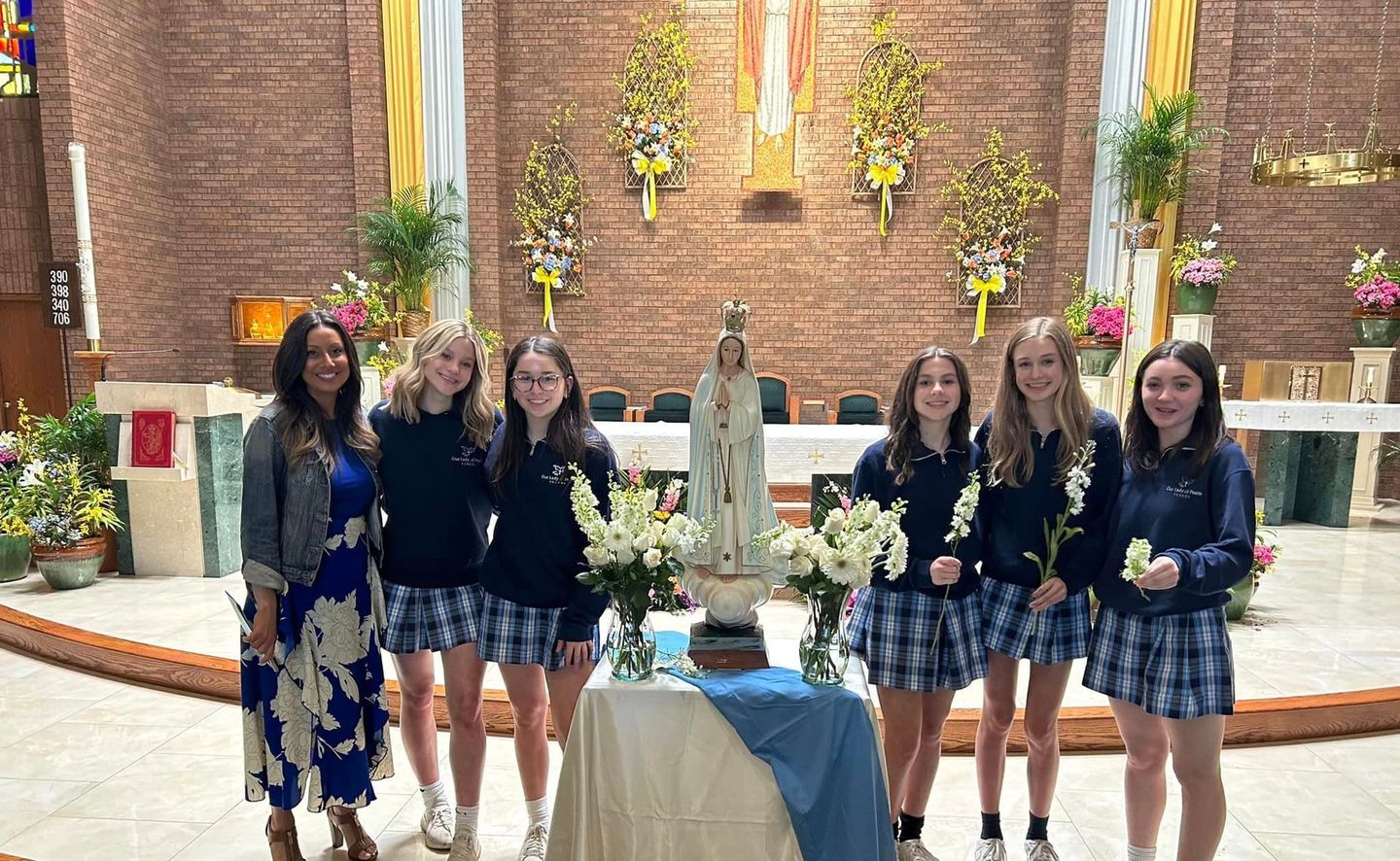 A group of girls standing in front of a statue in a church