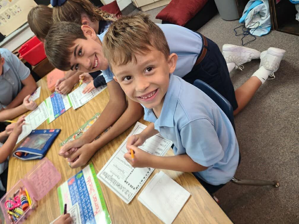 A group of children are sitting at a table and one of them is smiling