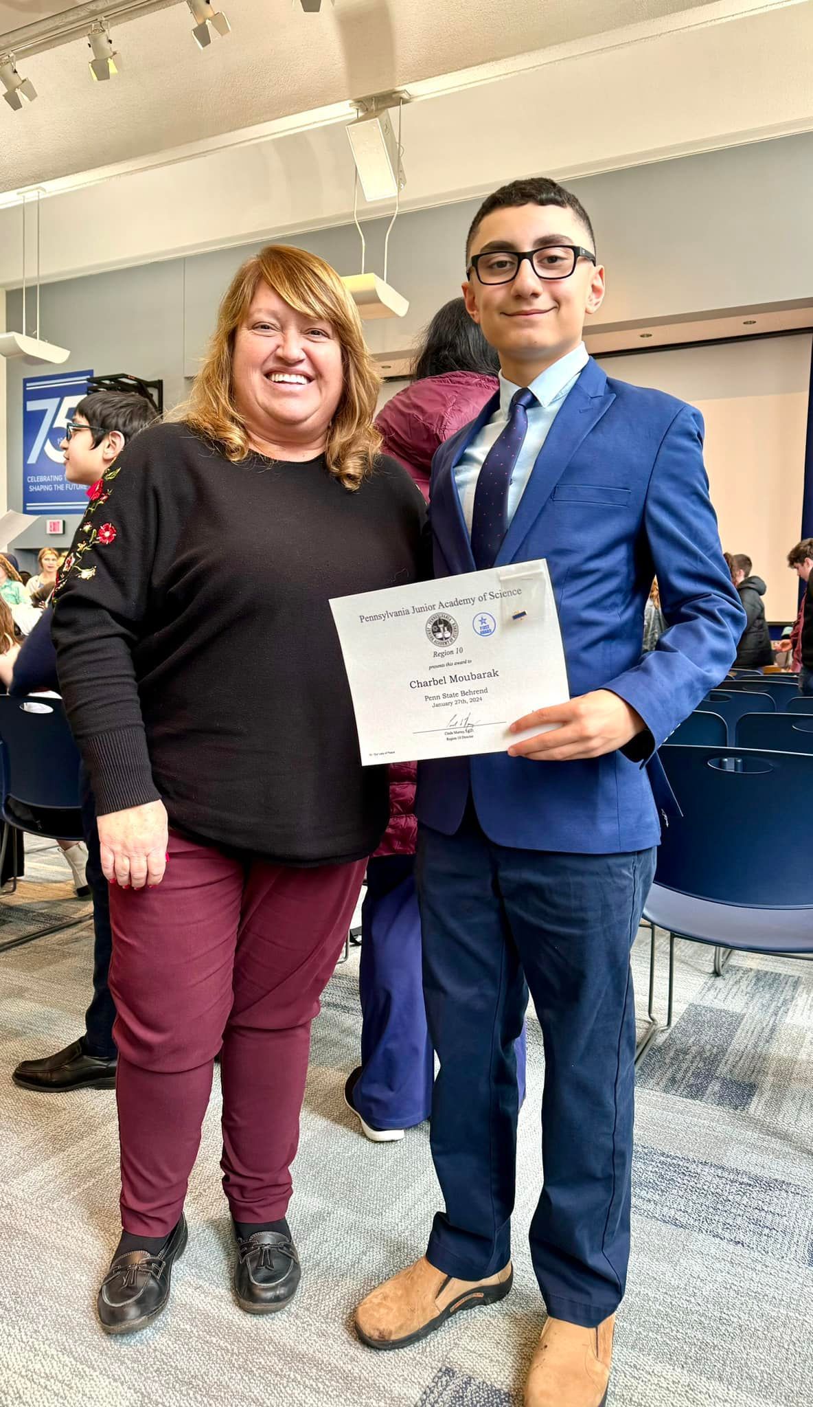 A man and a woman are posing for a picture while the man is holding a certificate