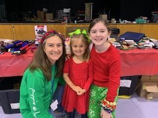 A woman in a green shirt is posing for a picture with two little girls.