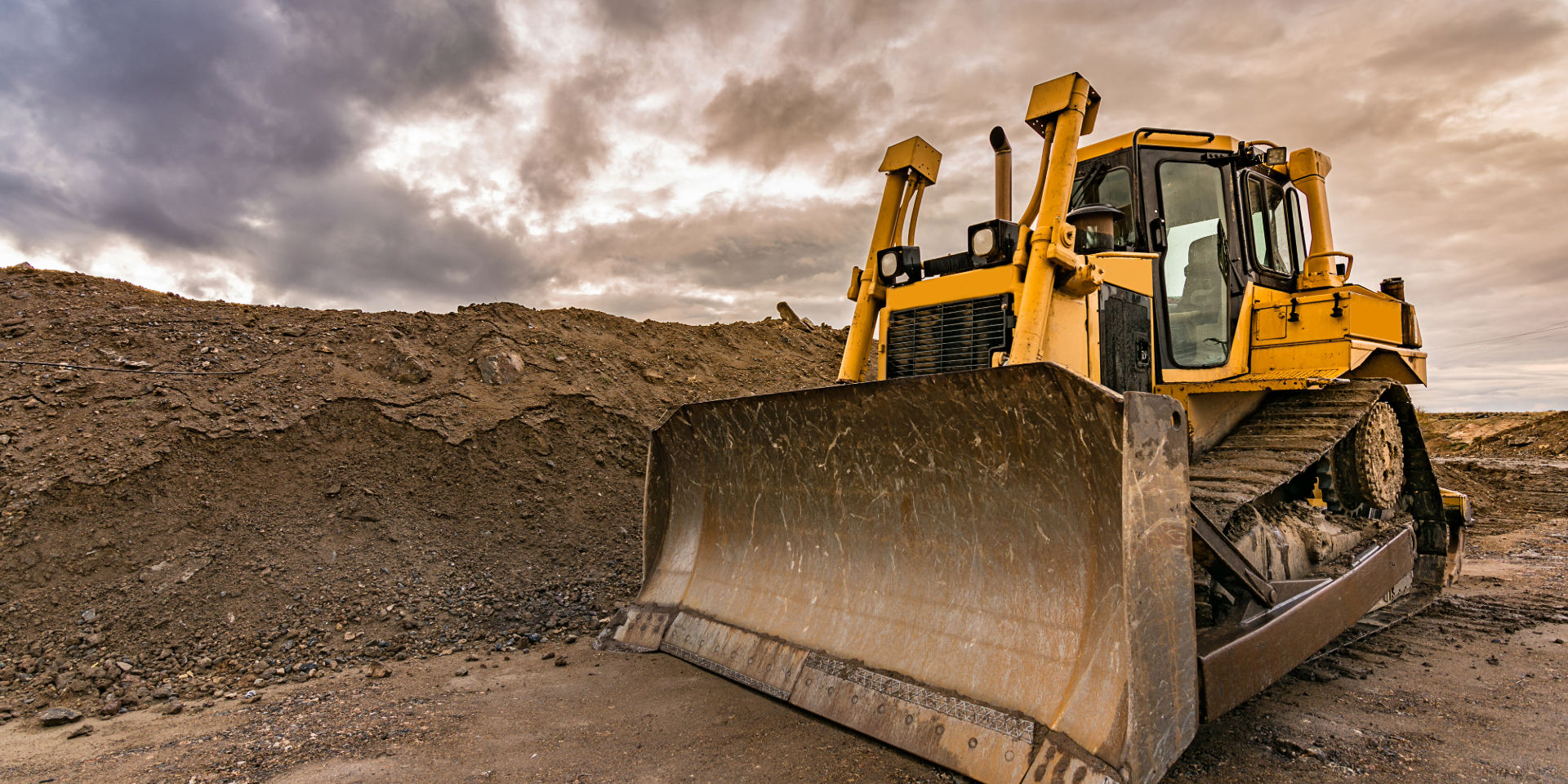Wheelbarrow filled with garden waste on green grass, hedge in the background.