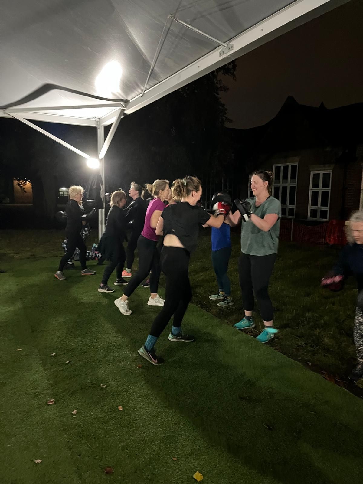 A group of people are doing exercises in a park at night