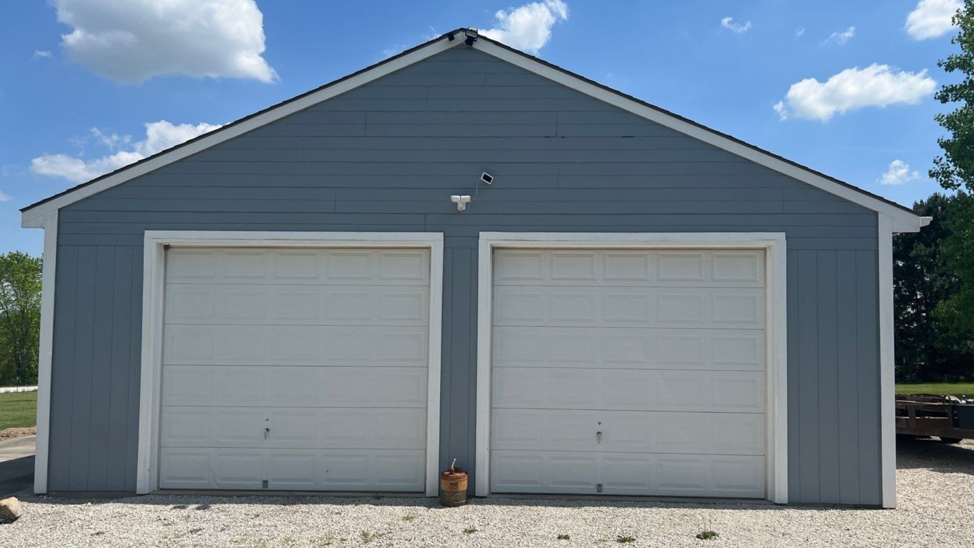 A garage with two white garage doors and a blue sky in the background
