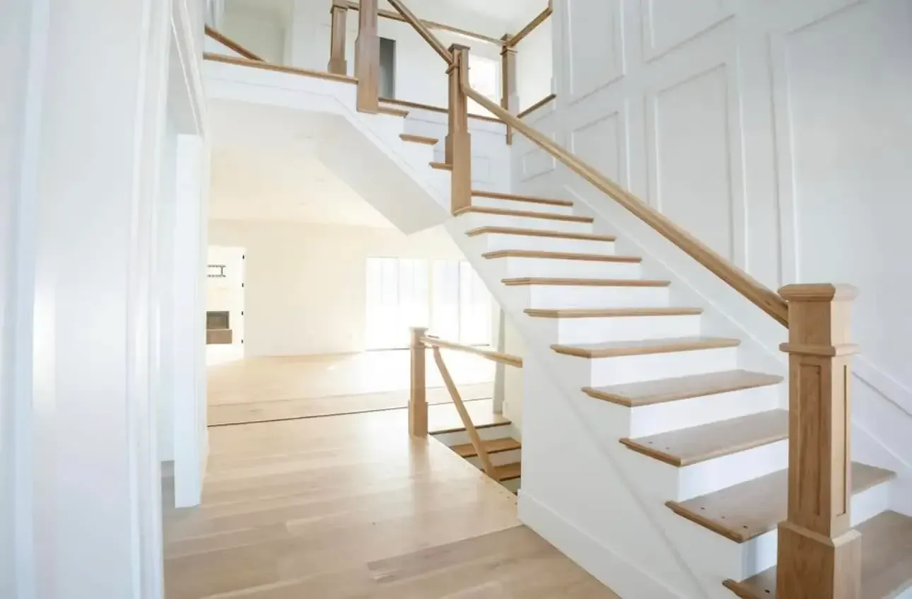 Bright, white interior with wooden staircase and handrails. Sunlight streams in, illuminating the space. Bright, white interior with wooden staircase and handrails. Sunlight streams in, illuminating the space.
