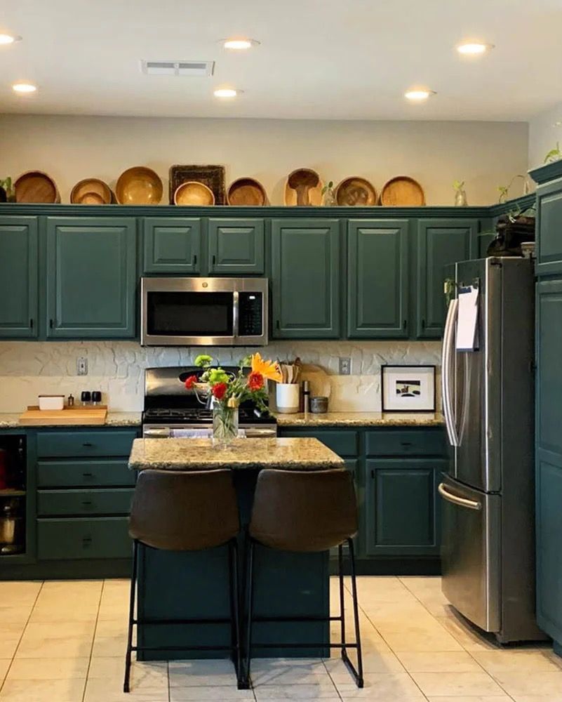 Dark teal kitchen with island and stainless steel appliances; plates on cabinets. Dark teal kitchen with island and stainless steel appliances; plates on cabinets.