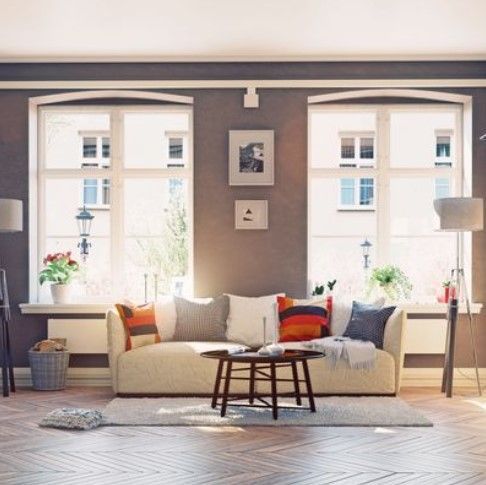 Living room with beige sofa, two large windows, wooden floor, and coffee table. Living room with beige sofa, two large windows, wooden floor, and coffee table.