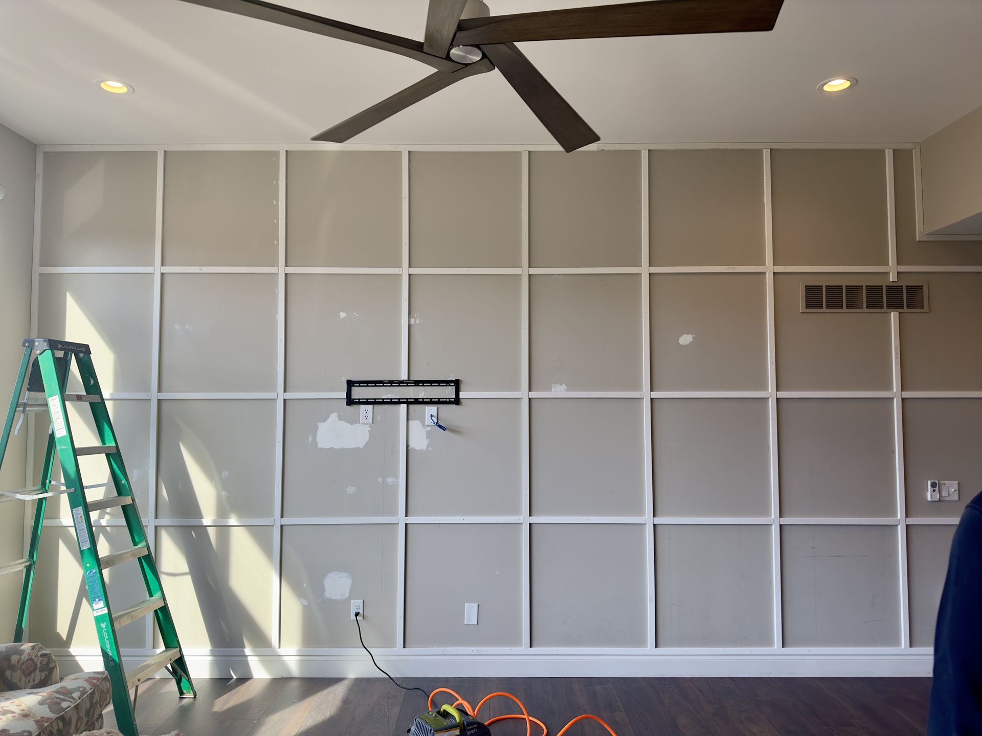 Wall with white grid trim, ladder, and wires.