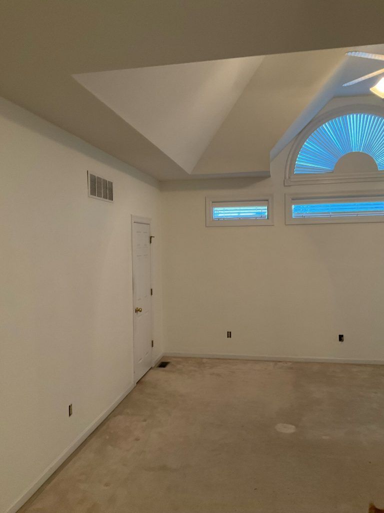 Empty room with white walls, carpeted floor, and arched window.