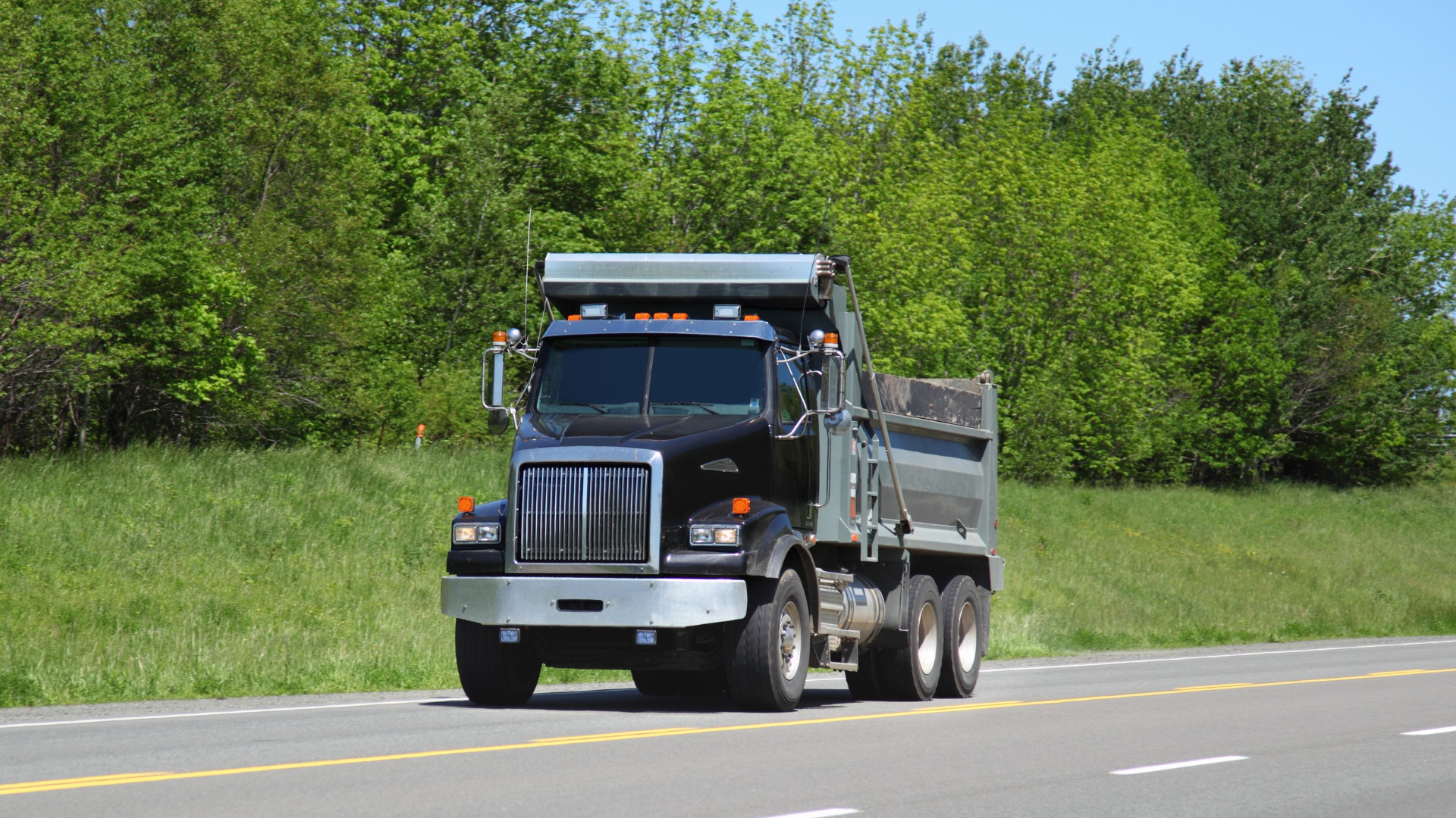 A red dumpster filled with cardboard boxes in a parking lot