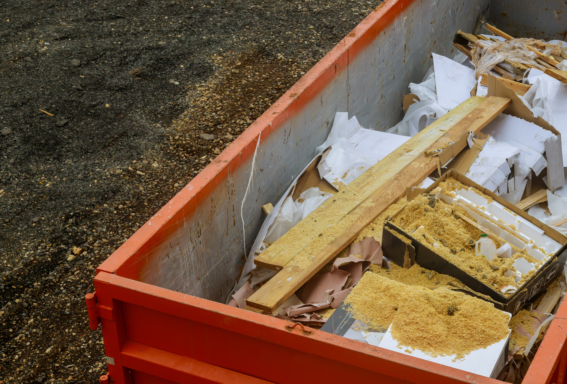 A large yellow house with a green dumpster in front of it
