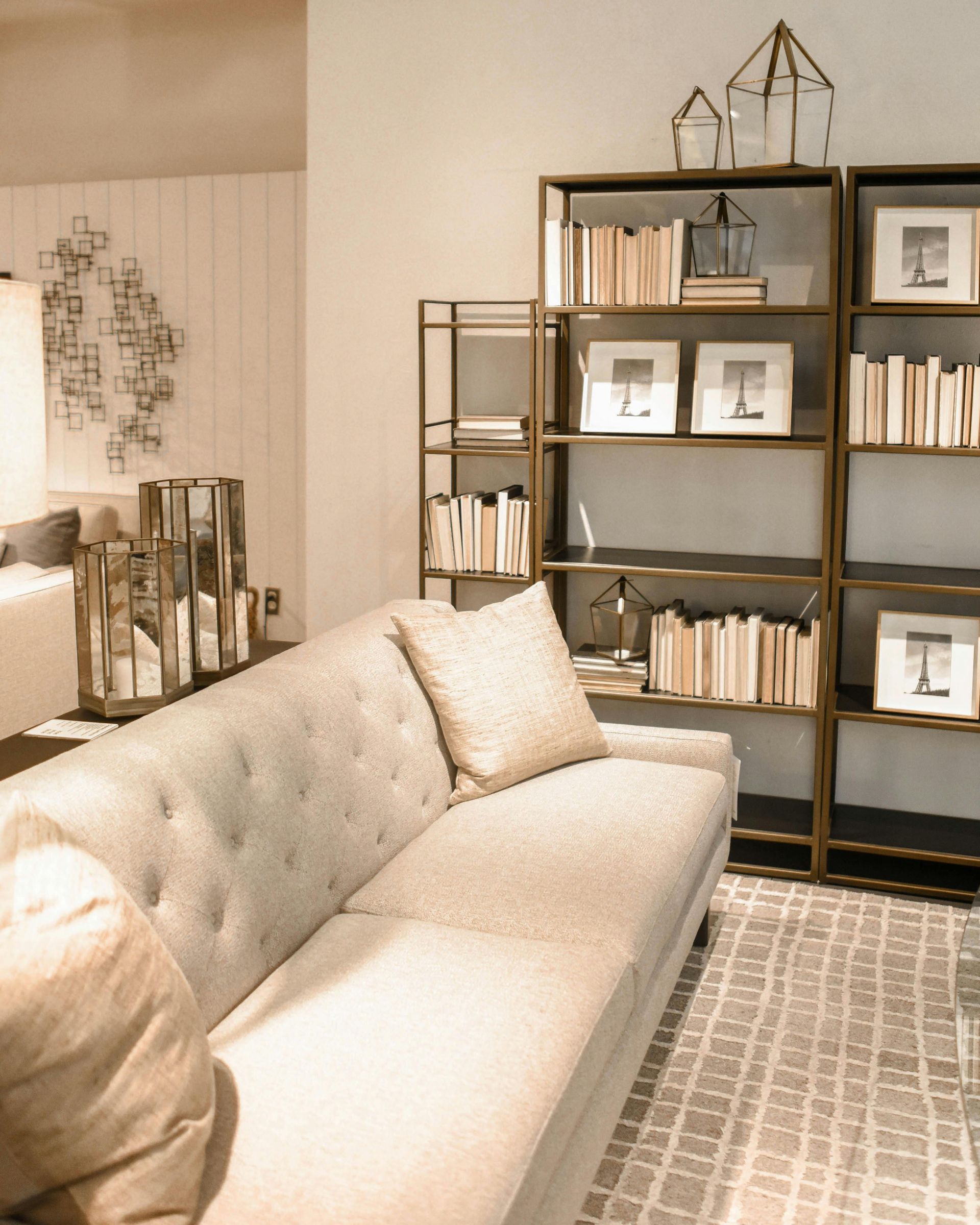 Beige sofa in front of a bookshelf filled with books, decorative items in a neutral-toned room.