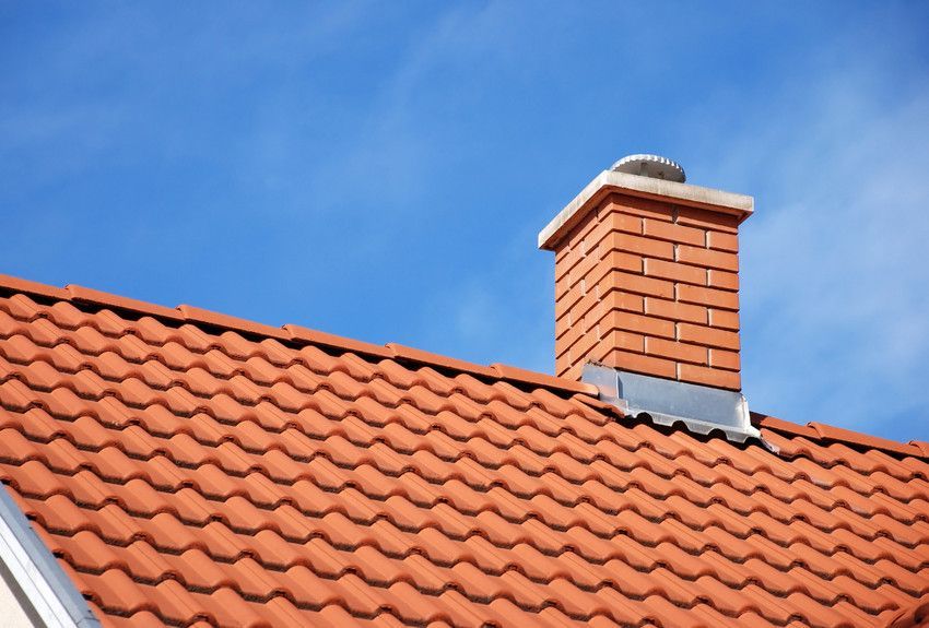 A brick chimney on top of a red tiled roof