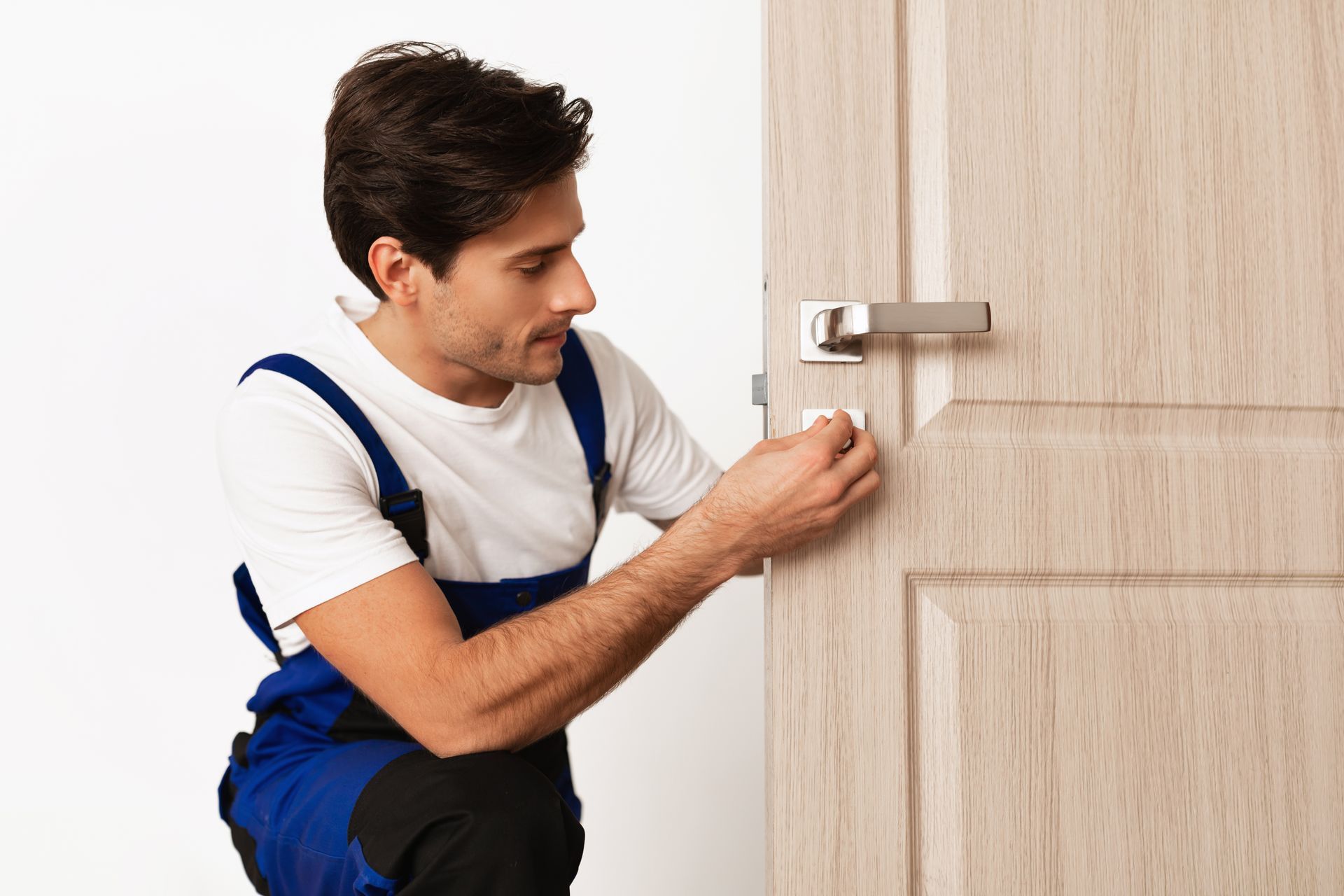 A skilled locksmith adjusts a wooden door lock for reliable operation.