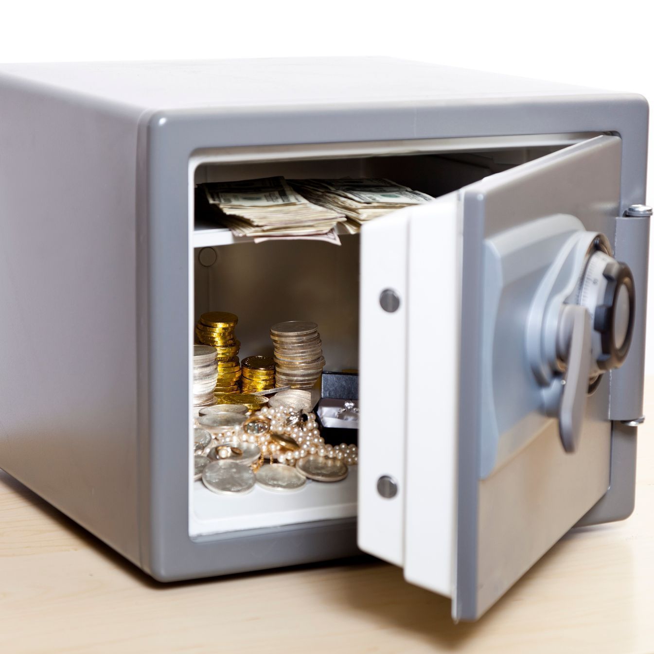A safe filled with coins and money with the door open.