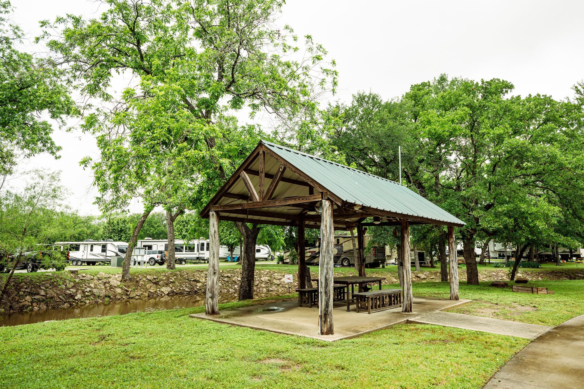 A picnic shelter with a table and chairs in a park.