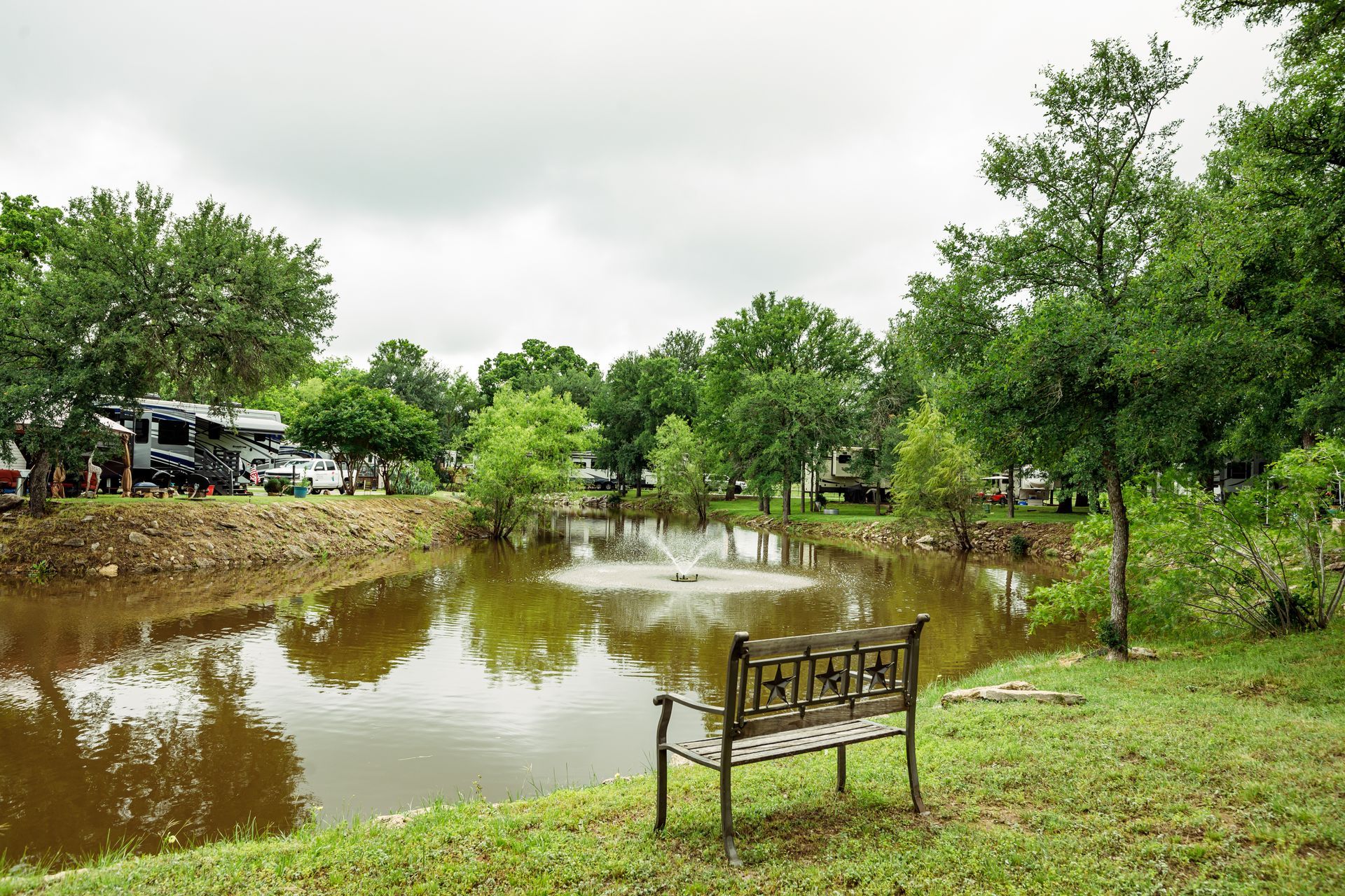 A bench is sitting next to a pond in a park.