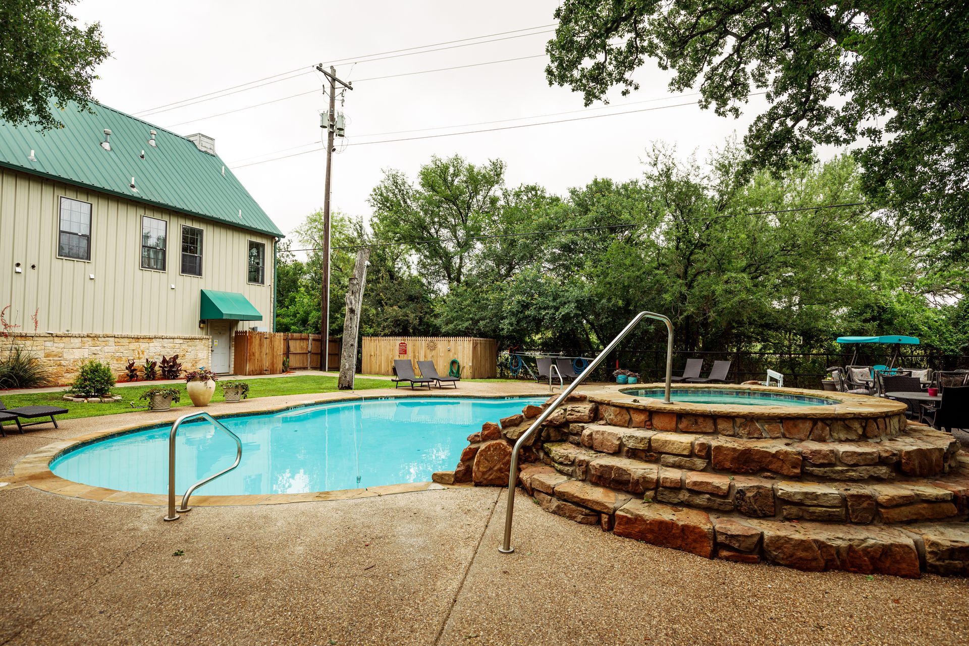 A large swimming pool with a hot tub in front of a building.