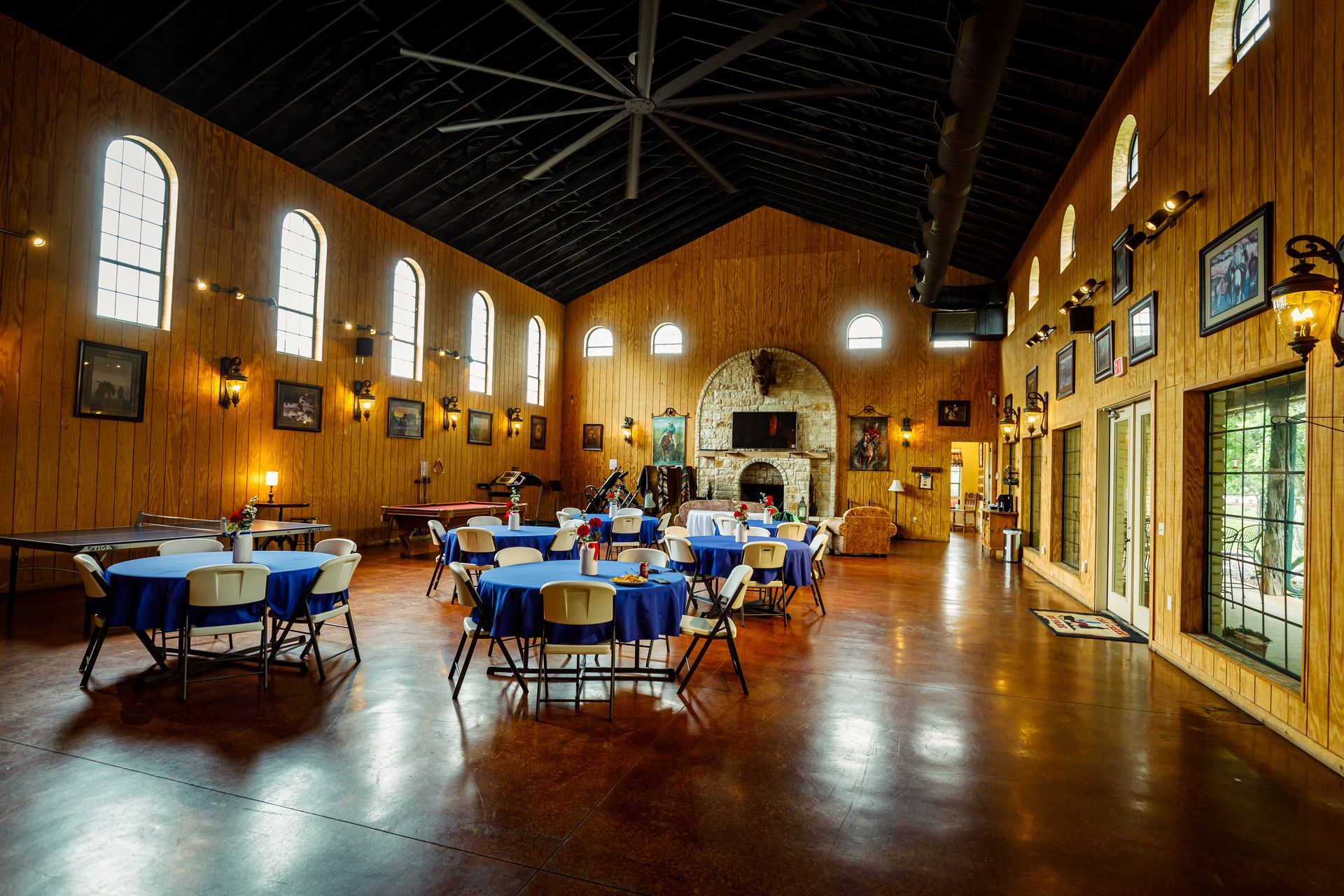 A large room with tables and chairs and a ceiling fan.
