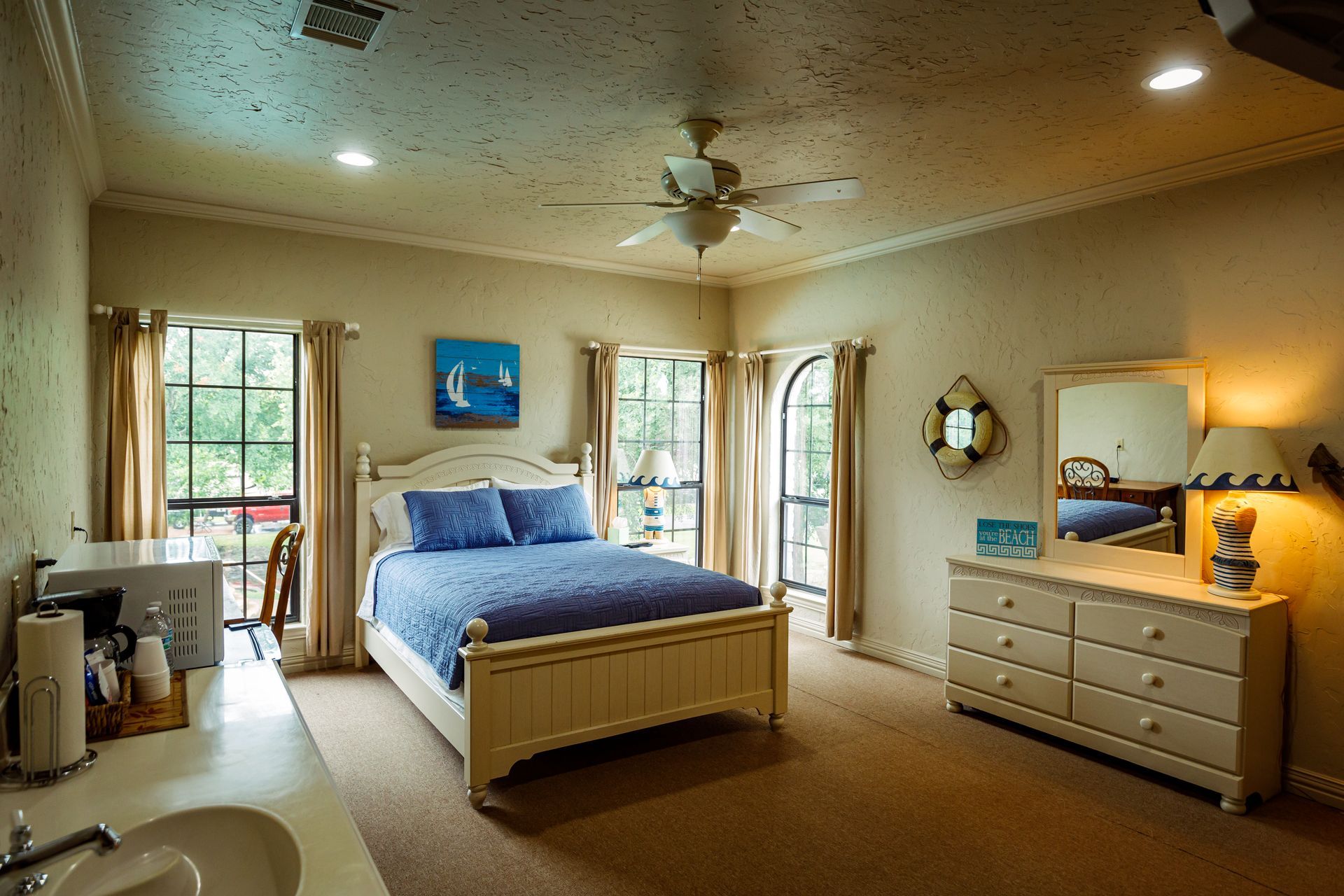 A bedroom with a king size bed , dresser , mirror and sink.