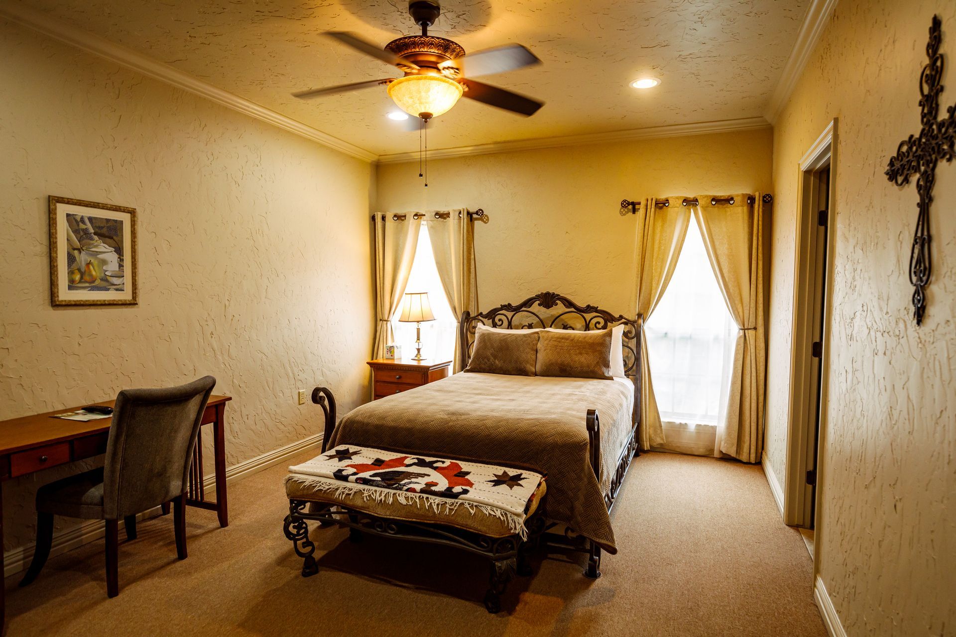 A bedroom with a bed , desk , chair and ceiling fan.