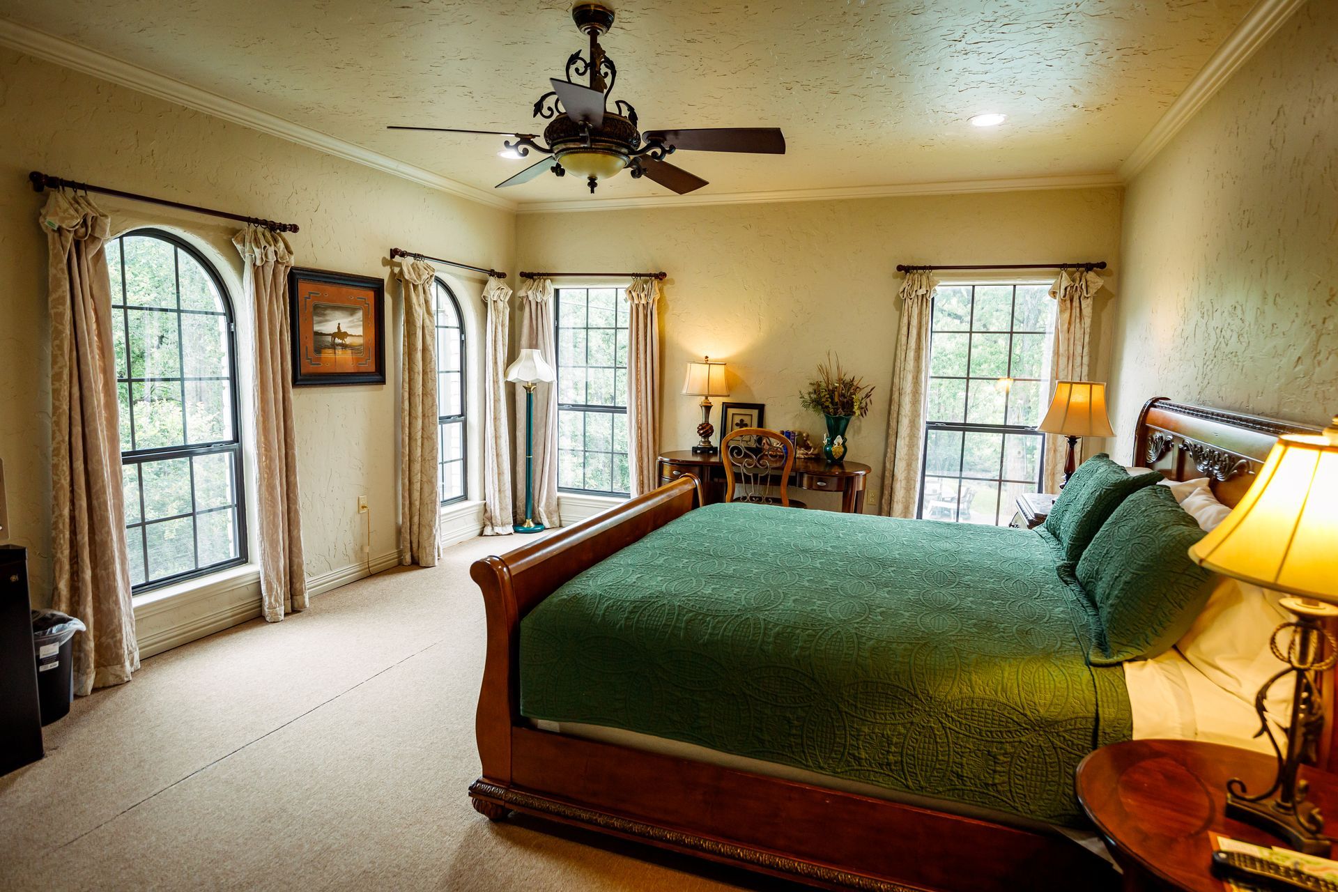 A bedroom with a large bed and a ceiling fan