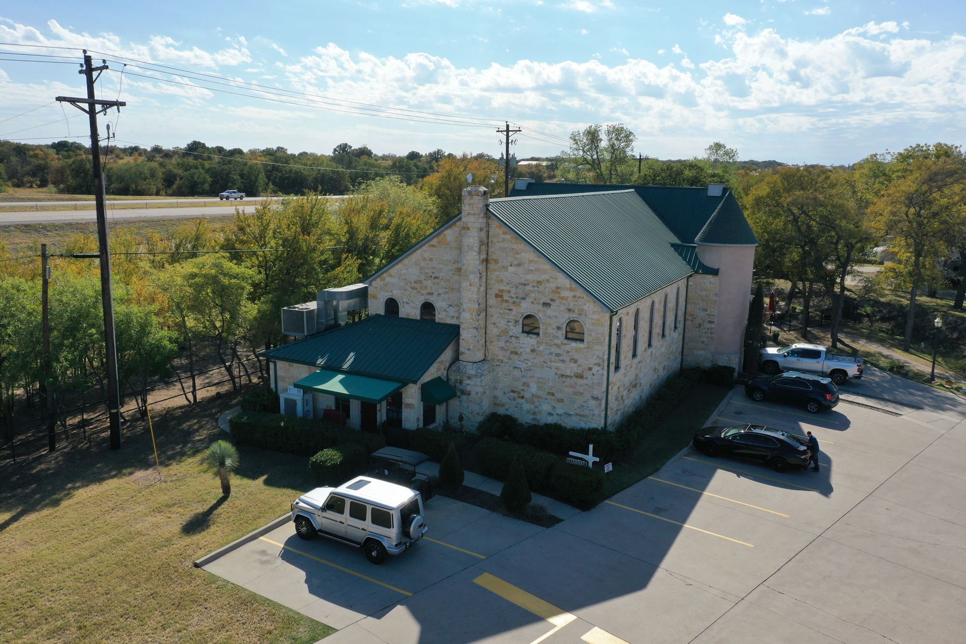 An aerial view of a building with a green roof and cars parked in front of it.