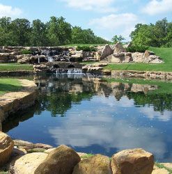 There is a pond with a waterfall in the background.