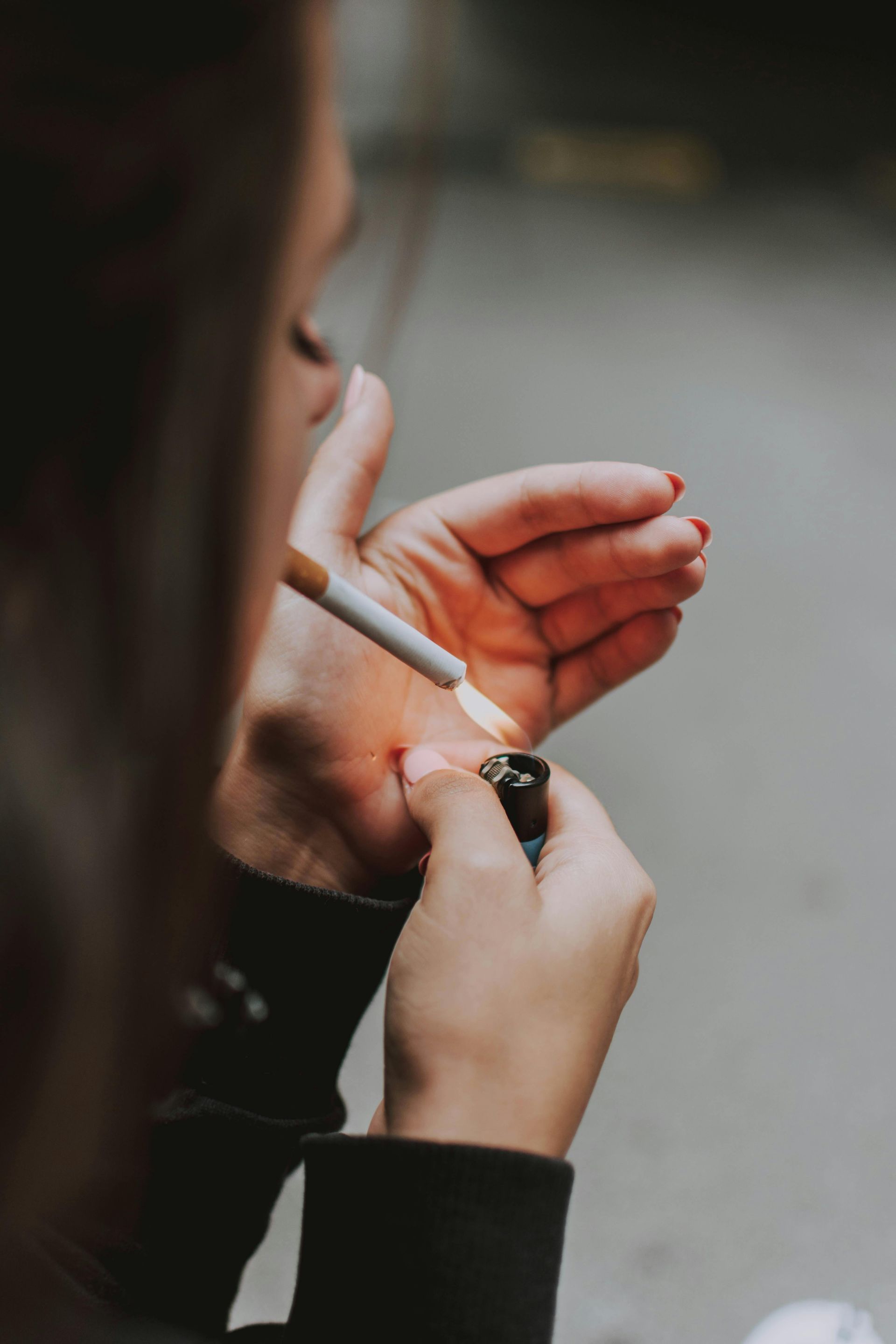 Woman lighting a cigarette with a lighter, hand close-up.
